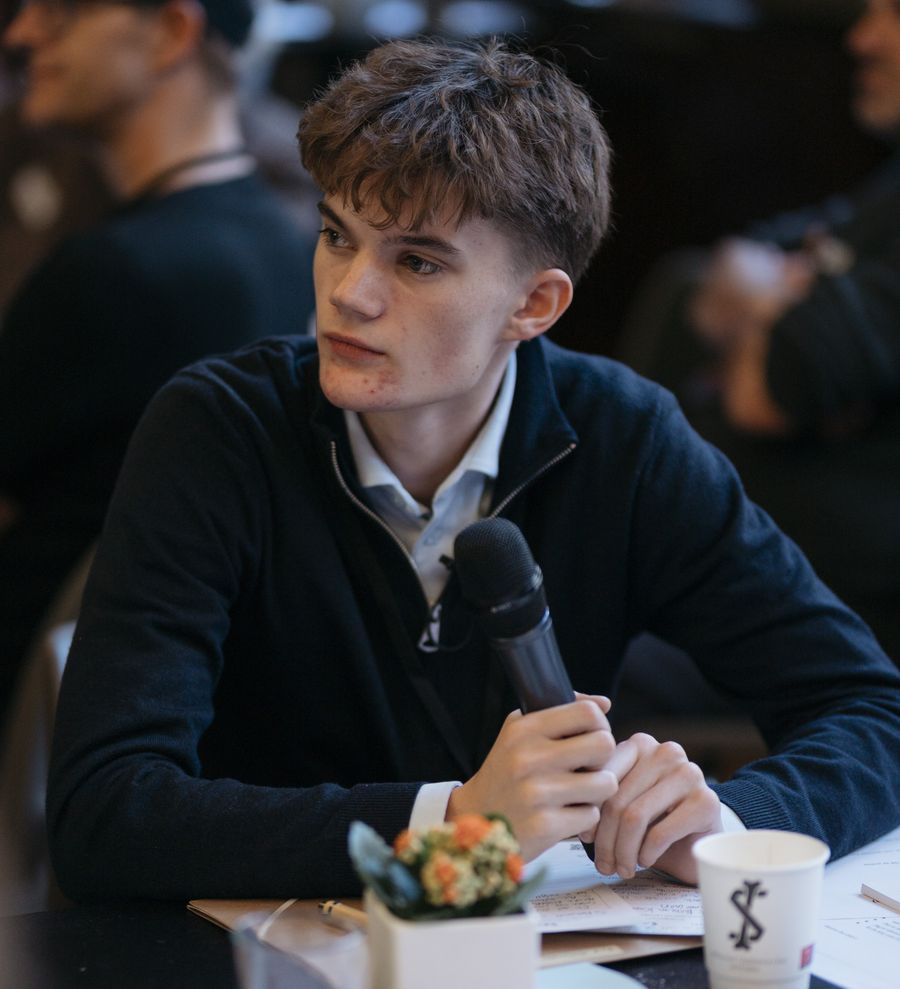 A young participant holds a microphone during a group discussion.
